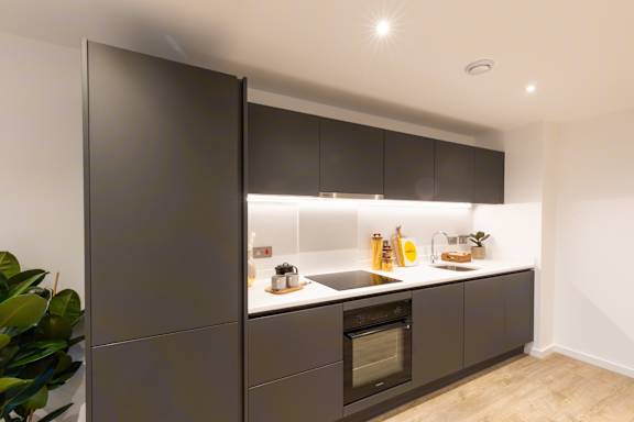A modern kitchen with dark brown cabinets and a black fridge.