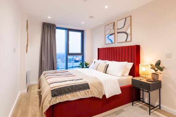 A bedroom with a red headboard and a large bed.