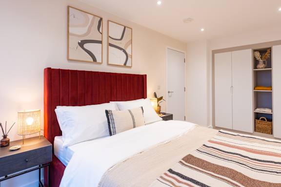 A bedroom with a red headboard and a white bed.