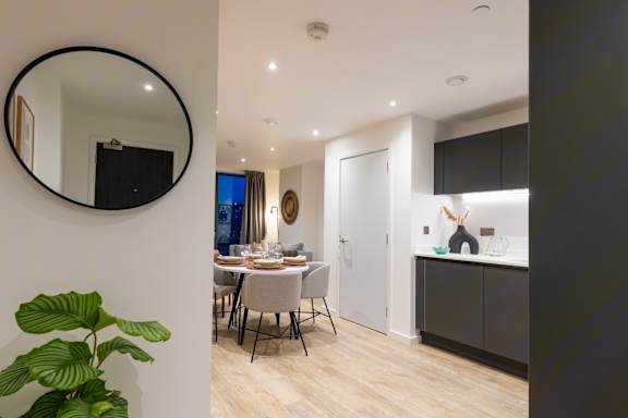 A modern dining room with a round mirror and a dining table set for two.