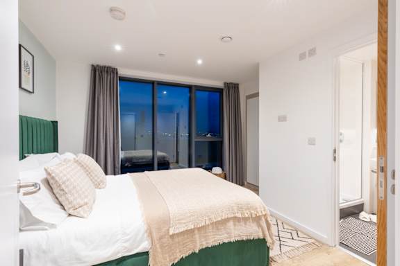 A bedroom with a large bed and a view of the city.