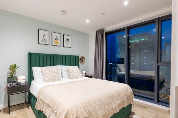 A bedroom with a large bed and a view of the city outside the window.