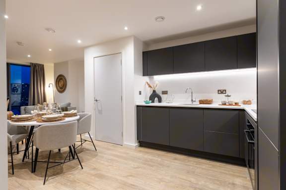 A modern kitchen with a dining table set for two.