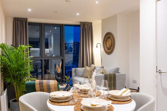 A dining table set for a meal with a view of the city outside the window.