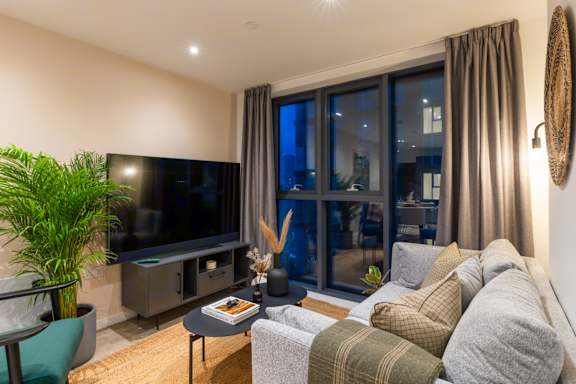 A modern living room with a large flat screen TV and comfortable seating.