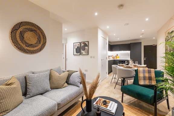 A living room with a grey couch and a woven basket on the wall.