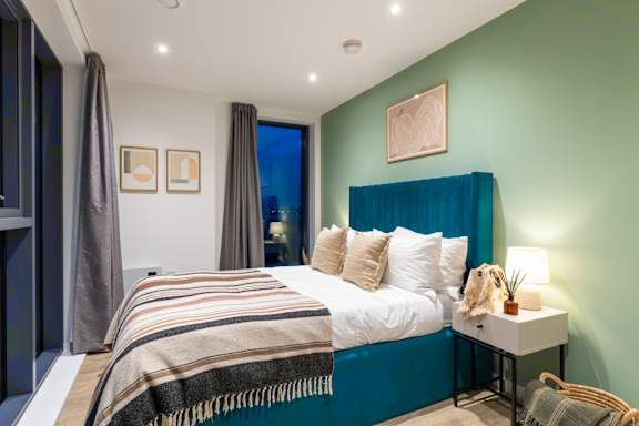 A bedroom with a bed, nightstand, and window.