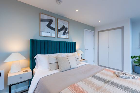 A bedroom with a large bed and a lamp on the nightstand.
