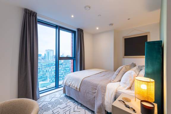 A bedroom with a large bed and a view of the city.