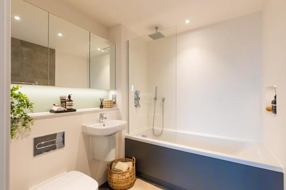 A white sink is in a modern bathroom with a white toilet and a white towel.