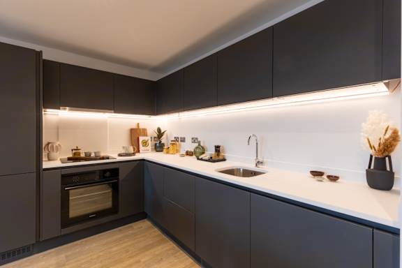 A modern kitchen with dark cabinets and a white countertop.