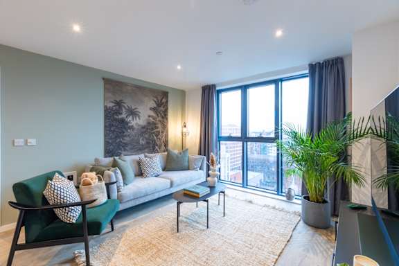 A living room with a green sofa and a large window.