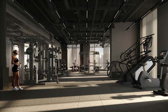 A woman is standing in a gym with a variety of exercise equipment.