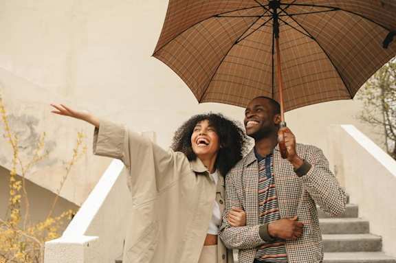 A man and woman are standing under an umbrella on a staircase.