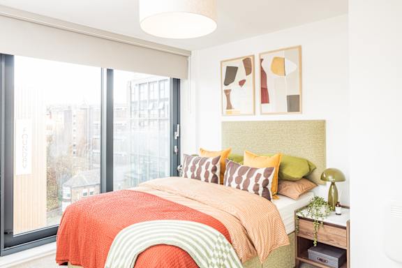 A bedroom with a bed, pillows, and a nightstand.