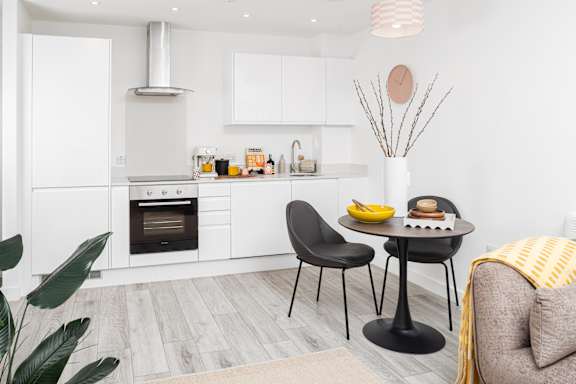 A modern kitchen with a dining table set for two.