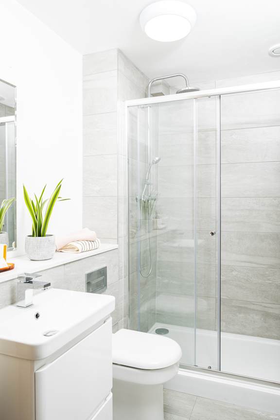 A white toilet sits next to a glass shower stall in a bathroom.
