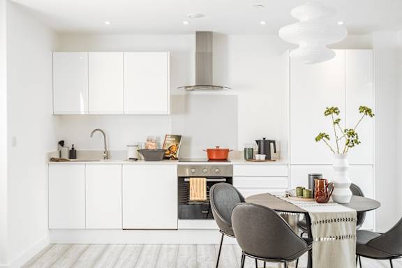 A modern kitchen with white cabinets and a dining table set for four.