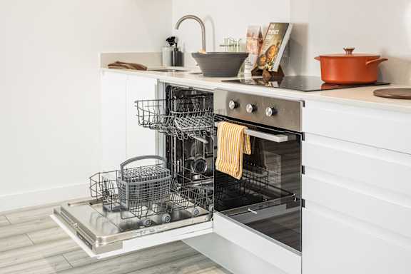 A modern kitchen with a stainless steel oven and a dish rack filled with dishes.