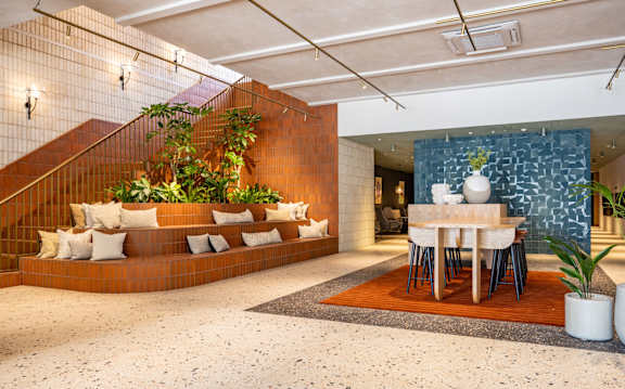 A modern interior with a staircase, a dining table, and a plant.