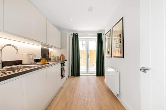 A kitchen with white cabinets and a wooden floor.