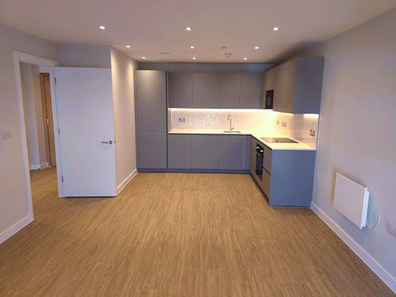 A kitchen with wooden floors and grey cabinets.