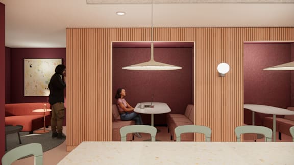 A woman is sitting at a table in a room with red walls and a wooden panelled ceiling.