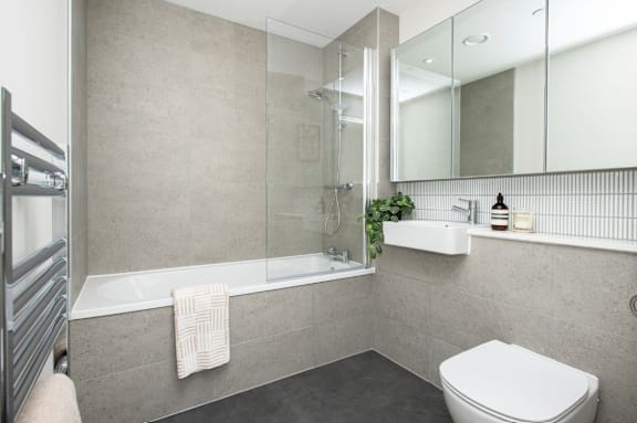 A modern bathroom with a white toilet, a glass shower enclosure, and a white sink.