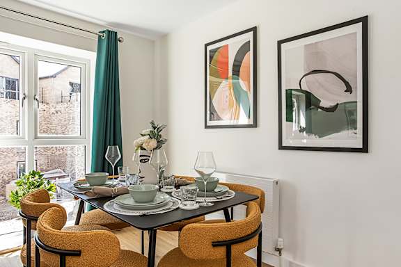 A dining room with a table set for two and two chairs.