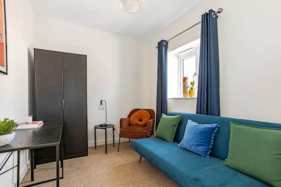 A living room with a blue couch and a black cabinet.