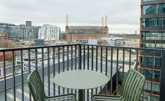 A balcony with a table and two chairs overlooking a cityscape.