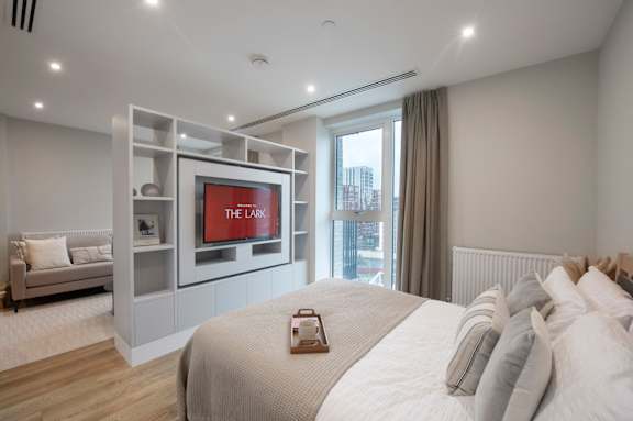A bedroom with a large bed and a television on the wall.