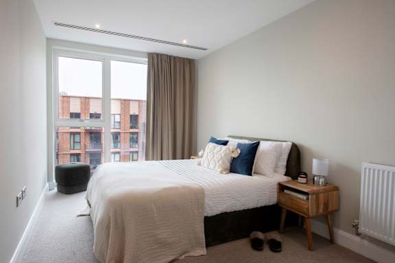 A bedroom with a large bed and a window overlooking a cityscape.
