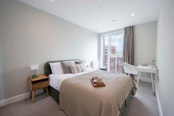A bedroom with a bed, desk, and chair.