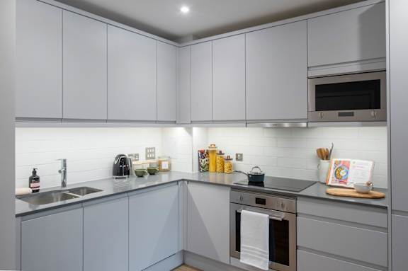 A modern kitchen with grey cabinets and stainless steel appliances.