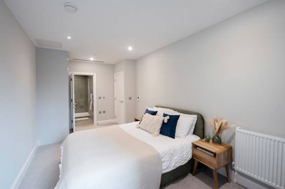 A bedroom with a bed, nightstand, and a window.