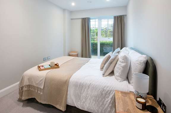 A bedroom with a large bed and a window with curtains.