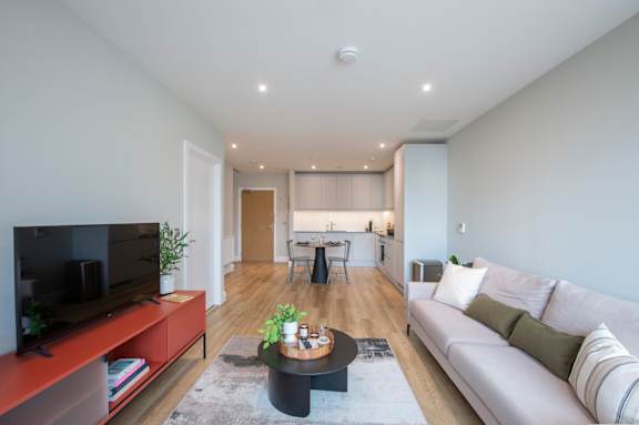 A modern living room with a television on the left and a sofa on the right.