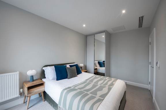A bedroom with a bed, nightstand, and a radiator.