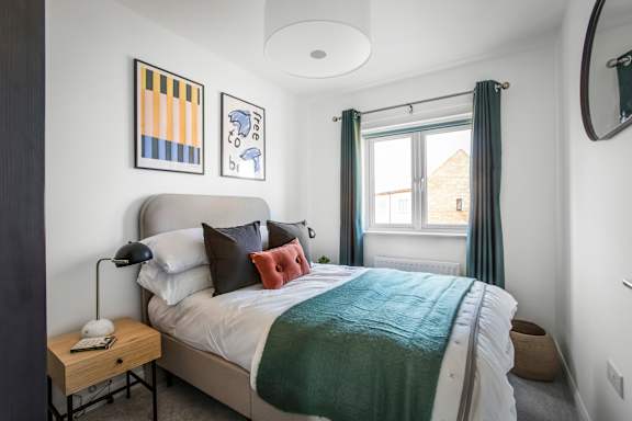 A bedroom with a bed, nightstand, and a window with curtains.