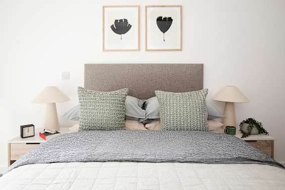 a bedroom with a bed and two pictures on the wall above it