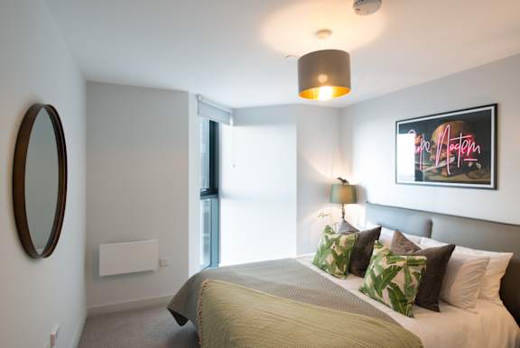 A bedroom with a large bed and a painting on the wall.