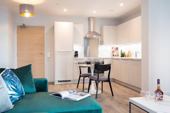 A modern kitchen with a teal couch and a magazine on it.