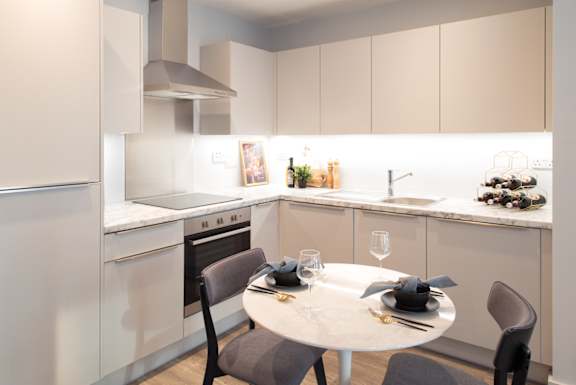 A modern kitchen with a dining table set for two.