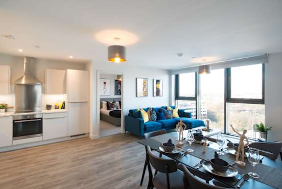 A modern kitchen with a blue couch in the living room.