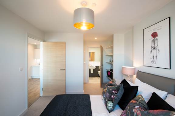 A bedroom with a bed, a lamp, and a framed picture on the wall.