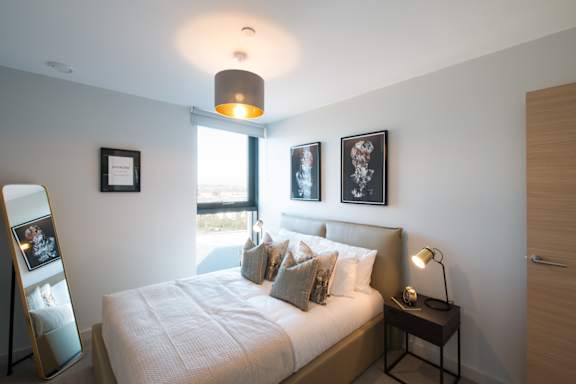 A bedroom with a bed, nightstand, and pictures on the wall.