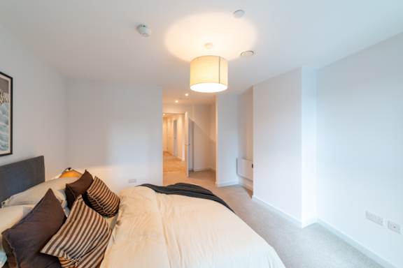A bedroom with a large bed and a painting on the wall.