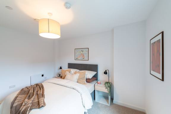 A bedroom with a bed, nightstand, and lamp.