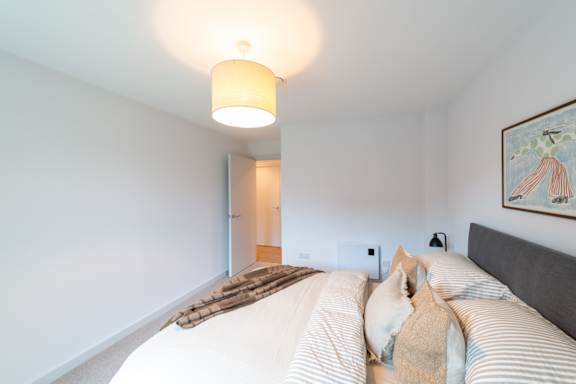 A bedroom with a bed, a lamp, and a painting on the wall.